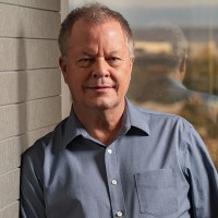 Chuck Price in portrait, leaning against a wall.